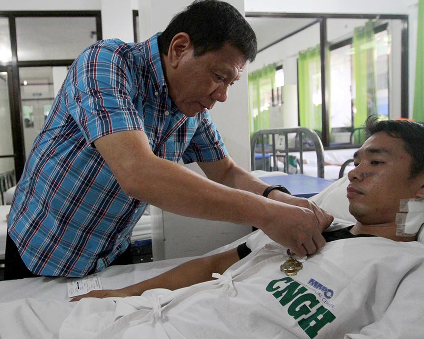 President Rodrigo Roa Duterte awards a medal to Cpl. Ruel Clavo during his visit at Camp General Basilio Navarro in Zamboanga City on November 25, 2016. Clavo was wounded in a clash with Abu Sayyaf members in Lamitan City, Basilan recently. MARCELINO PASCUA/Presidential Photo