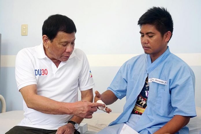 President Rodrigo Duterte examines the injuries of Corporal Abelardo Suela Jr., one of the soldiers wounded in an encounter with the New People’s Army at Brgy. Lamanan in Calinan District, Davao City on February 16, 2017. The President personally visited the wounded soldiers at Camp Panacan Station Hospital in Davao City on February 17, 2017 to award them with Wounded Personnel Medals as well as cash assistances. PCOO Davao
