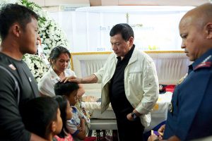 President Rodrigo Roa Duterte comforts one of the children of the late PO1 Rholly Benelayo during his wake visit at the Bansalan Municipal Lobby in Davao del Sur on March 9, 2017. Benelayo is one of the four police officers who were killed in an ambush by suspected members of the New People's Army in the municipality of Bansalan, Davao del Sur on March 8, 2017. Also in the photo is Philippine National Police Director General Ronald dela Rosa. ROBINSON NIÑAL/Presidential Photo