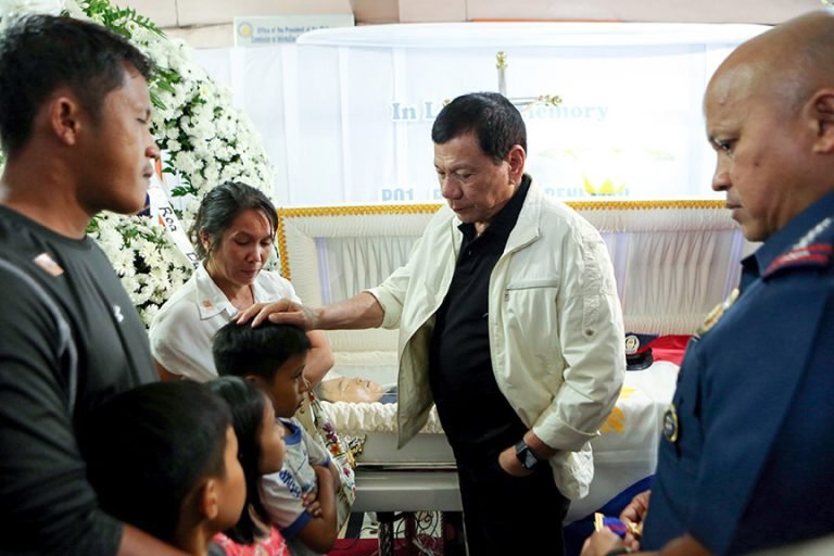 President Rodrigo Roa Duterte comforts one of the children of the late PO1 Rholly Benelayo during his wake visit at the Bansalan Municipal Lobby in Davao del Sur on March 9, 2017. Benelayo is one of the four police officers who were killed in an ambush by suspected members of the New People's Army in the municipality of Bansalan, Davao del Sur on March 8, 2017. Also in the photo is Philippine National Police Director General Ronald dela Rosa. ROBINSON NIÑAL/Presidential Photo