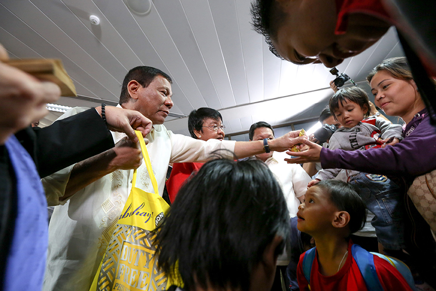 President Rodrigo Duterte is assisted by Social Welfare Secretary Judy Taguiwalo  as he shares his pasalubong of chocolates to the children of the 160 repatriated Overseas Filipino Workers (OFWs) who were granted amnesty after they were found working illegally in the Kingdom Saudi Arabia. The President welcomed the repatriated 'runaway' OFWs and provided them with cash assistance upon his arrival at the Ninoy Aquino International Airport Terminal 1 on April 17, 2017 following his successful visits to the Kingdom of Saudi Arabia, Bahrain and Qatar. KING RODRIGUEZ/ Presidential Photo