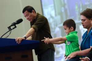 POSING LIKE A PRO: Stingray, the grandson of President Rodrigo Duterte (in green polo) pose like enjoying his fingers holding a gun while his grandfather talks about imposing stiffer government regulations to gun buyers.-PHOTO: PPD