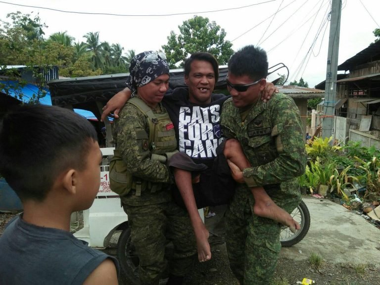 Army soldiers drop firearms to carry PWD who  receive  relief goods, wheelchair